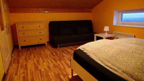a bedroom with a bed and a couch and a window at Holiday House Koceri in Ķekava