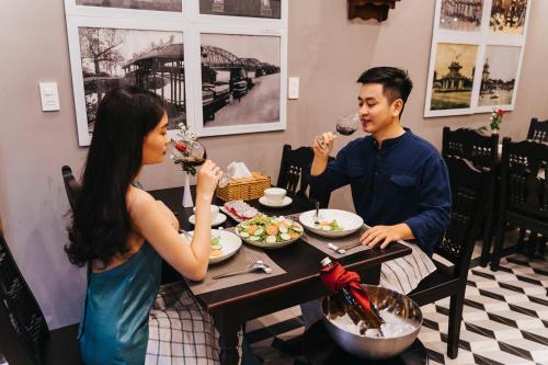 a man and woman sitting at a table drinking wine at Hue 1962 INN in Hue