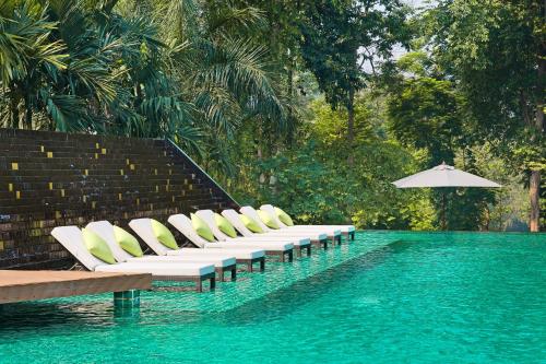 a row of lounge chairs next to a swimming pool at Mida Resort Kanchanaburi - SHA PLUS in Sai Yok