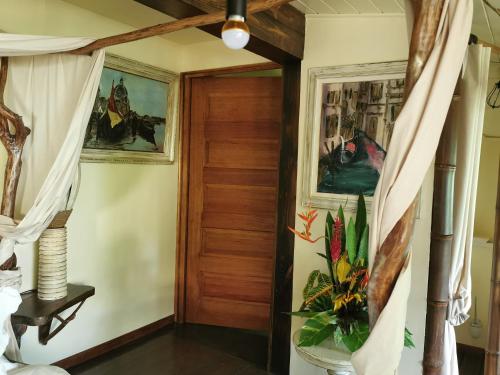 a hallway with a wooden door and paintings on the walls at Hôtel Fenua Mata'i'oa in Papetoai