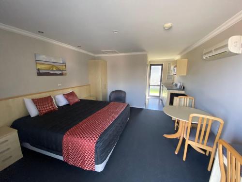 ブレナムにあるGrove Park Motor Lodgeのベッドとテーブルが備わるホテルルームです。