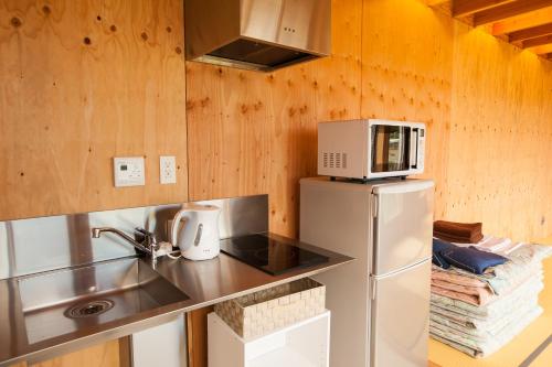 a small kitchen with a refrigerator and a microwave at Sunset Breeze Hota in Kyonan