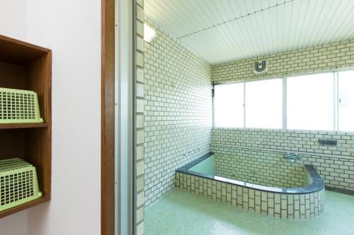 a bathroom with a tub in a room with windows at Sunset Breeze Hota in Kyonan