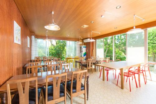 鋸南町的住宿－保田日落微風酒店，餐厅设有木桌、椅子和窗户。