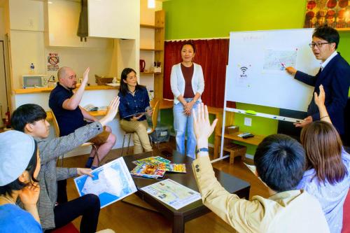 a group of people standing in a room with their hands up at ゲストハウス ルルル 最大12名可 合宿 大家族 団体旅行にオススメ in Kochi