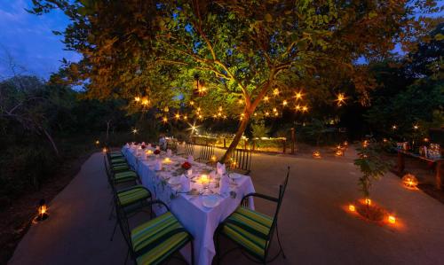 a long table with white tablecloths and chairs with lights at Sawai Madhopur Lodge - IHCL SeleQtions in Sawāi Mādhopur