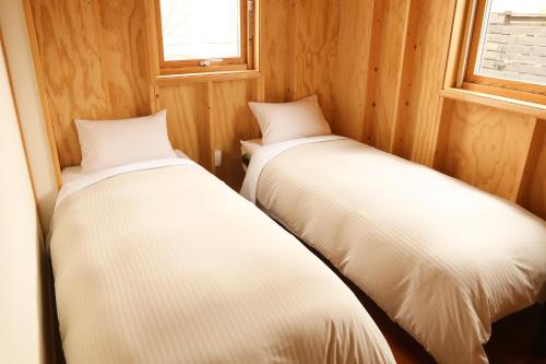 2 letti in una piccola camera con pareti in legno di Phottage inn Biei a Biei