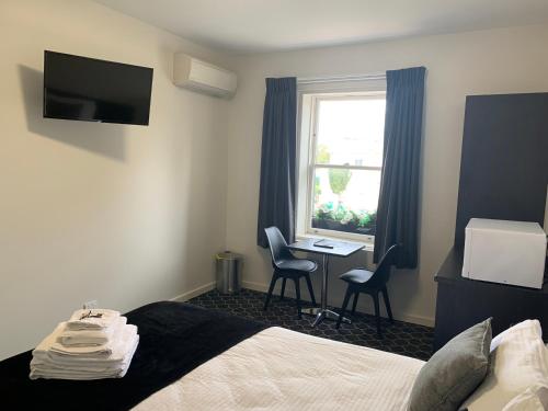 a hotel room with a bed and a desk and a window at Queens Arms Hotel in Longford