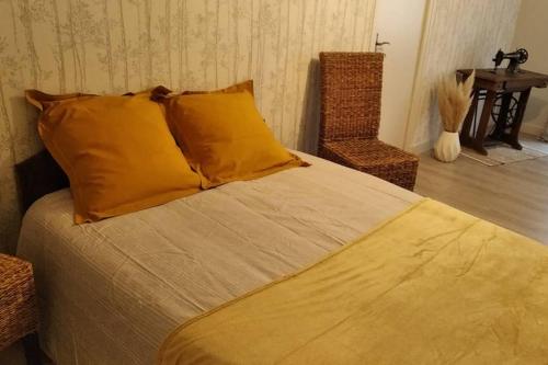 a bedroom with a bed with yellow pillows and a table at Le gîte de Georgette in Cour-Cheverny