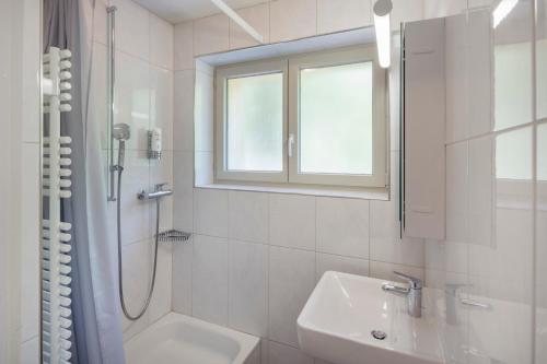 a white bathroom with a sink and a shower at Crans-Montana Youth Hostel in Crans-Montana