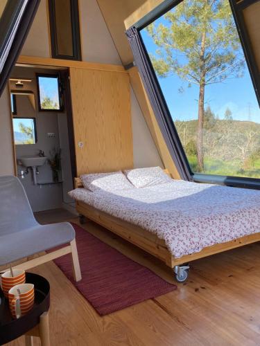 a bed in a room with a large window at Uxa Paraiso in Penela