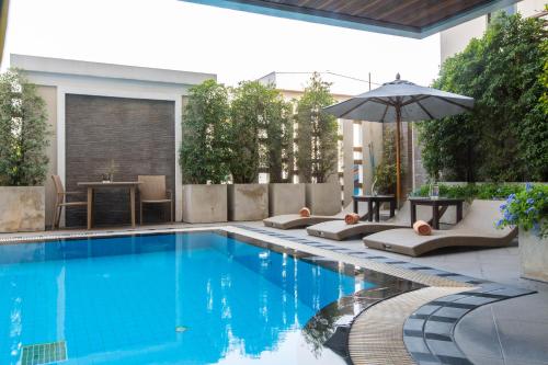 a swimming pool with lounge chairs and an umbrella at Mida Hotel Don Mueang Airport in Bangkok