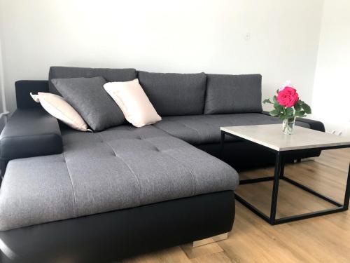 a grey couch with a table and a vase of flowers at Apartment Loyd, Tolmin - Most na Soči in Most na Soči