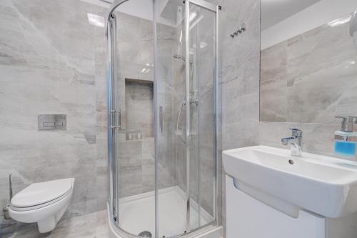 a bathroom with a shower and a sink and a toilet at Apartamenty Rondo in Świnoujście