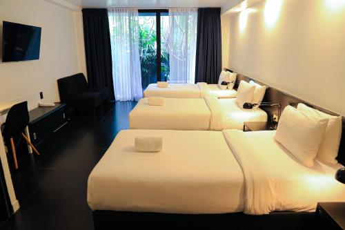 チェンマイにあるBED プラシン-大人専用のベッド4台とデスクが備わるホテルルームです。
