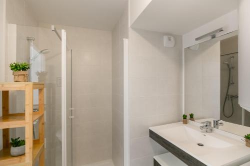 une salle de bain blanche avec un lavabo et une douche dans l'établissement L'Escapade Malouine, à Saint-Malo