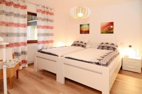 a bedroom with a white bed and a table at Ferienwohnung Marion in Ennepetal