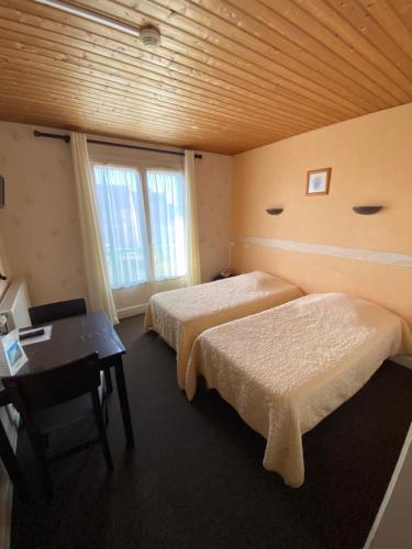 a room with two beds and a desk and a window at Le Lyon Vert in Commentry