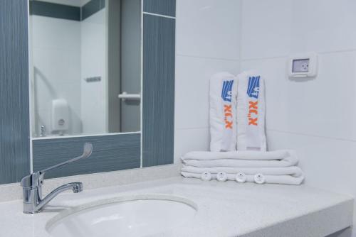 uma casa de banho com lavatório, espelho e toalhas em HI - Ein Gedi Hostel em Ein Gedi