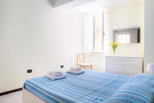 Centro Storico Oltretorrente Apartment في بارما: غرفة نوم بيضاء مع سرير أزرق مع مناشف عليها