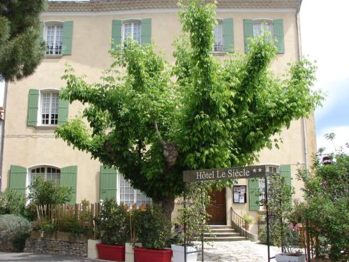 um edifício com uma árvore em frente em Hôtel Le Siècle em Mazan