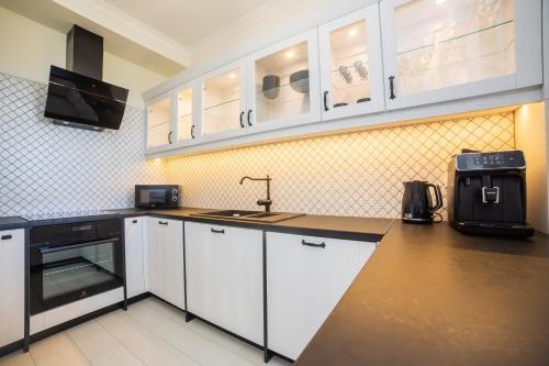 a kitchen with white cabinets and a sink at Apart Harmony - Apartament Hampton in Puck