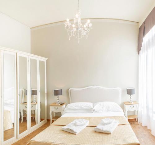 a white bedroom with a bed and a chandelier at Rialto Canal View With Terrace and Balcony by Wonderful Italy in Venice