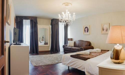a bedroom with a bed and a couch and a chandelier at Rialto Canal View With Terrace and Balcony by Wonderful Italy in Venice