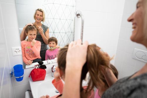 a woman and a child brushing their hair in front of a mirror at Palladium de Champéry in Champéry