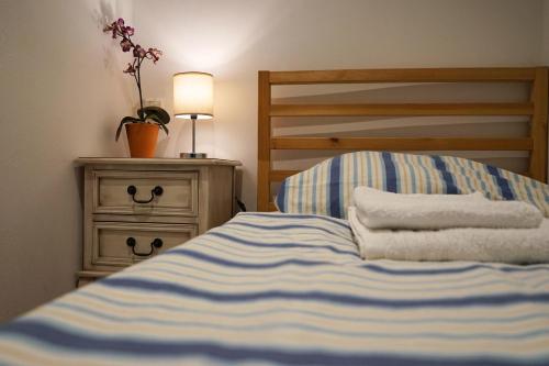 a bed with blue and white striped sheets and a nightstand at Monteurwohnung Oyten bei Bremen A1 dat Landhuus in Oyten