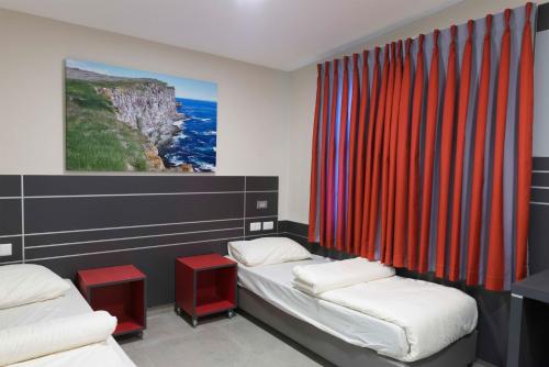 a room with two beds and red curtains at HI - Haifa Hostel in Haifa