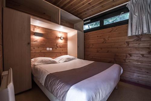 um quarto com uma cama e uma parede de madeira em Les Chalets by Le Marintan em Saint-Michel-de-Maurienne
