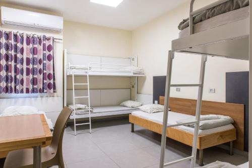 a dorm room with bunk beds and a desk at HI - Tel Hai Hostel in Tel H̱ay