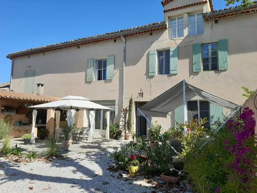 a large building with an umbrella and some flowers at le Mas d'Hubert in LʼIsle-sur-la-Sorgue