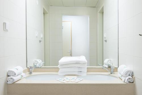 a bathroom with a sink with a mirror and towels at HI - Pkiin Hostel in Buqei‘a