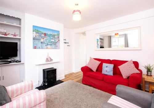 a living room with a red couch and a fireplace at Seashell Cottage in Deal