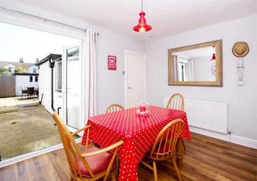 a dining room with a red table and chairs at Seashell Cottage in Deal