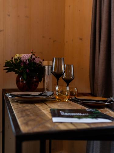 a table with two wine glasses and a vase of flowers at Ferienhäuser Saalemaxx in Rudolstadt