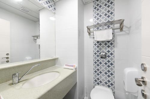 ein Badezimmer mit einem Waschbecken, einem WC und einem Spiegel in der Unterkunft HI Agron - Jerusalem Hostel in Jerusalem