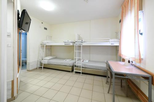 a room with three bunk beds and a table at HI Agron - Jerusalem Hostel in Jerusalem