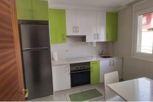 La cuisine est équipée de placards verts et blancs et d'un réfrigérateur. dans l'établissement Casa IRIENSE VUT-CO-004308, à Padrón
