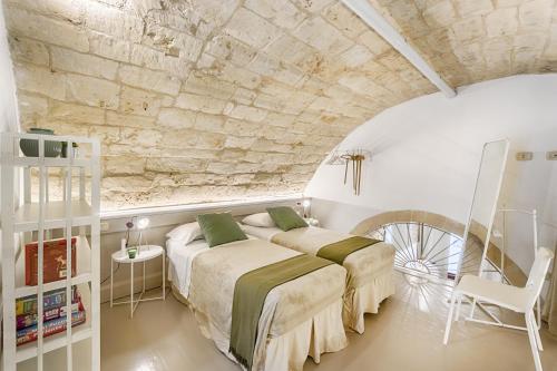 two beds in a room with a stone wall at Mario Leggio 83, gocce di Sicilia in Ragusa
