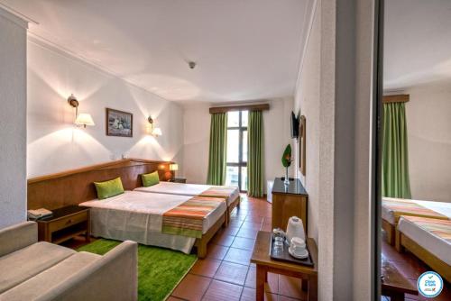 um quarto de hotel com duas camas e um sofá em Colina do Mar em Albufeira