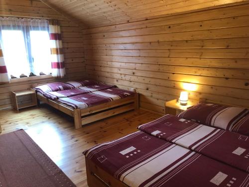 a room with two beds in a log cabin at Domki "Na Dworskiej" Polańczyk 696-025-331 in Polańczyk