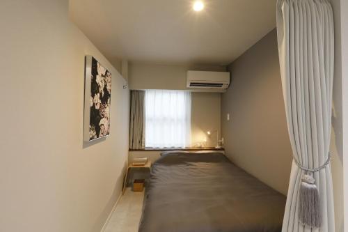 a small bedroom with a bed and a window at コンドミニアムHARU 那覇県庁前 201 in Naha