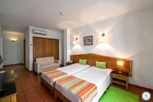 a hotel room with a bed and a chair at Colina do Mar in Albufeira