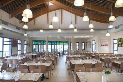 a dining room with tables and chairs and windows at HI - Beit Shean Hostel in Bet Sheʼan