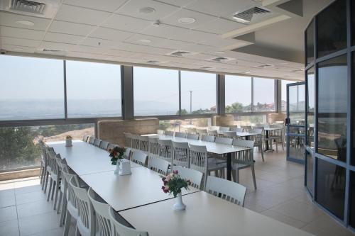 a dining room with tables and chairs and large windows at HI - Beit Shean Hostel in Bet Sheʼan