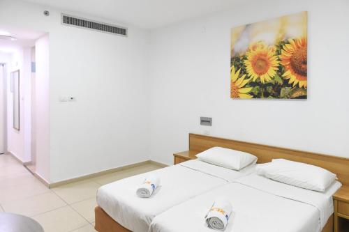 two beds in a room with a painting on the wall at HI - Beit Shean Hostel in Bet Sheʼan