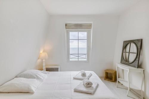 een witte slaapkamer met een groot wit bed en een spiegel bij Le Grand Sillon in Saint-Malo